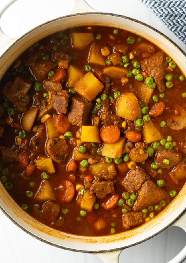 Top down Mulligan stew with chopped potatoes, carrots, peas, and chunks of beef.