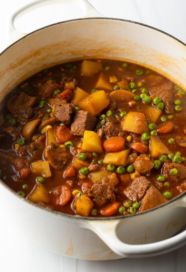 Chopped carrots, celery, onion, mushrooms, and potatoes with chunks of beef in a dutch oven for Irish beef stew