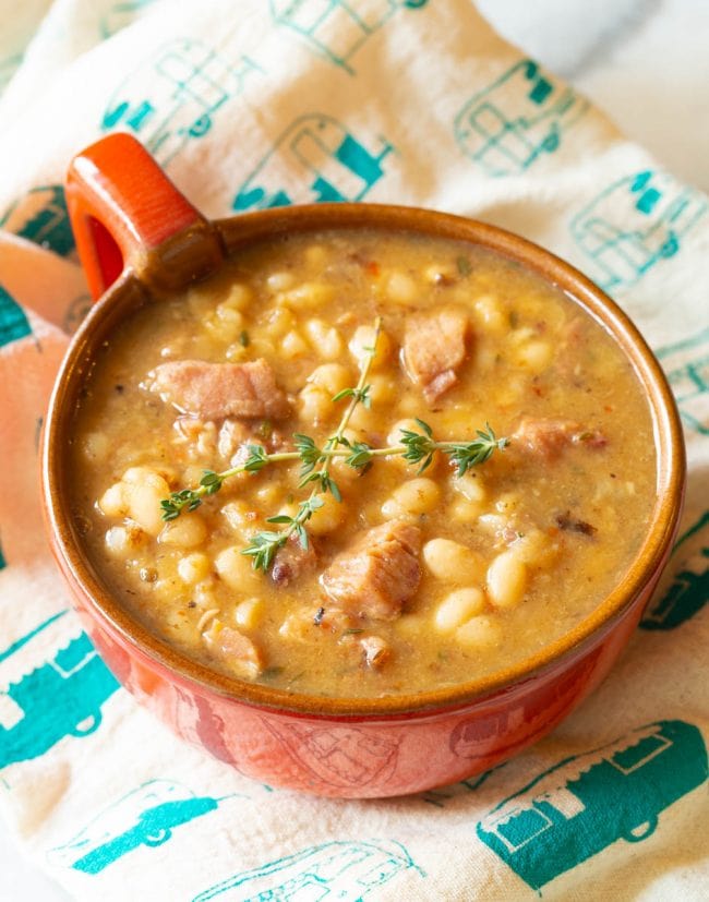 Single serving of this ham and bean soup recipe with a fabric napkin in the background 
