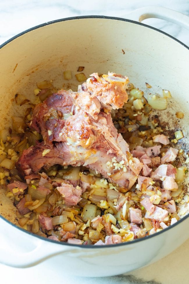 Ham bone in a dutch oven with onions and aromatics with it. 