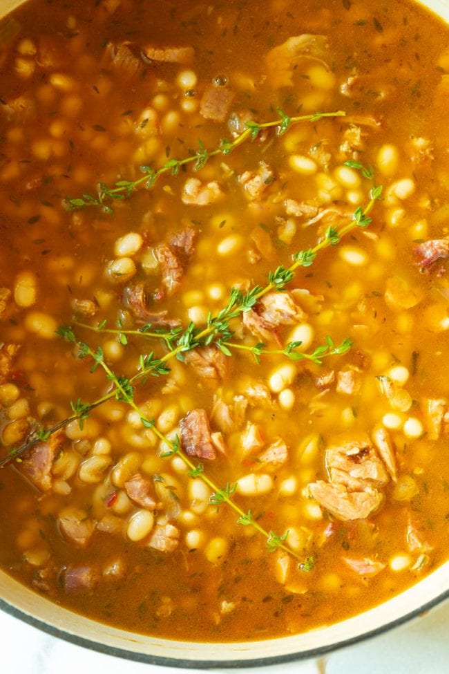 Ham and Bean Soup - Top view of the pot full topped with some sprigs of thyme leaves 
