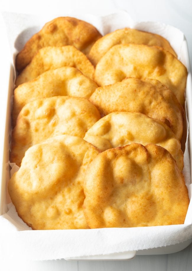 Fry bread tortillas in a baking dish lined with paper towel.