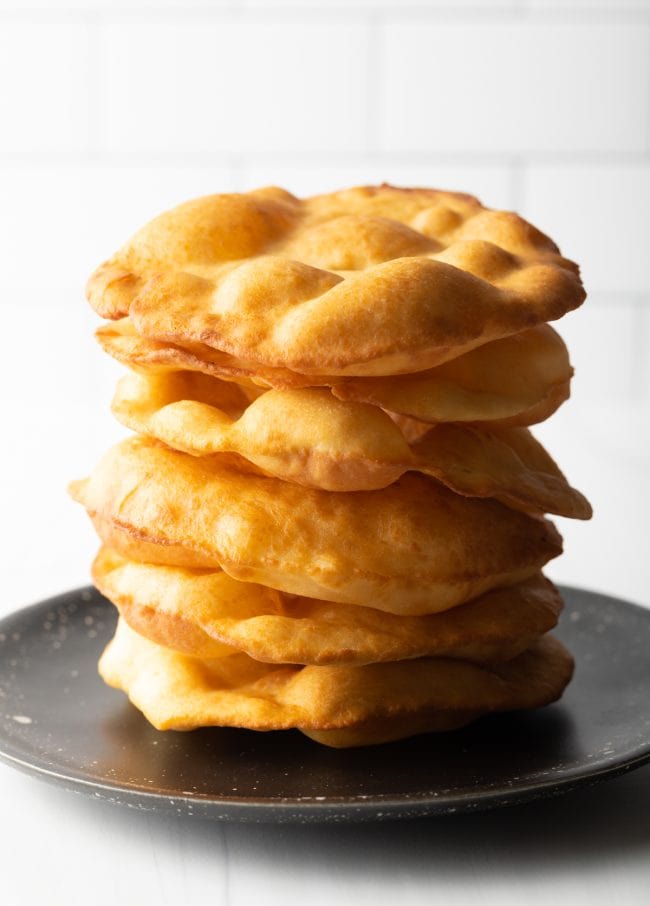 large stack of Navajo fry bread on a black plate. 