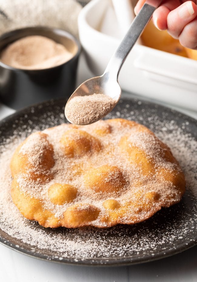 Indian Fry Bread being sprinkled with cinnamon sugar. 