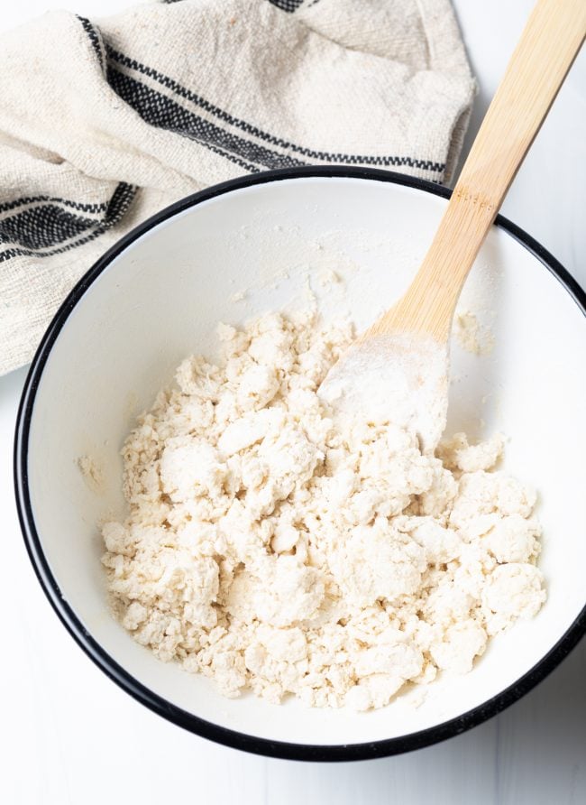 Fry bread dough being mixed with a wooden spoon in a mixing bowl. 