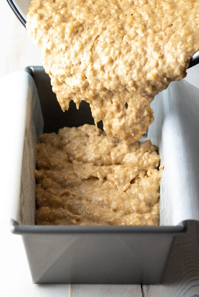 Banana bread batter going into a prepared loaf pan.