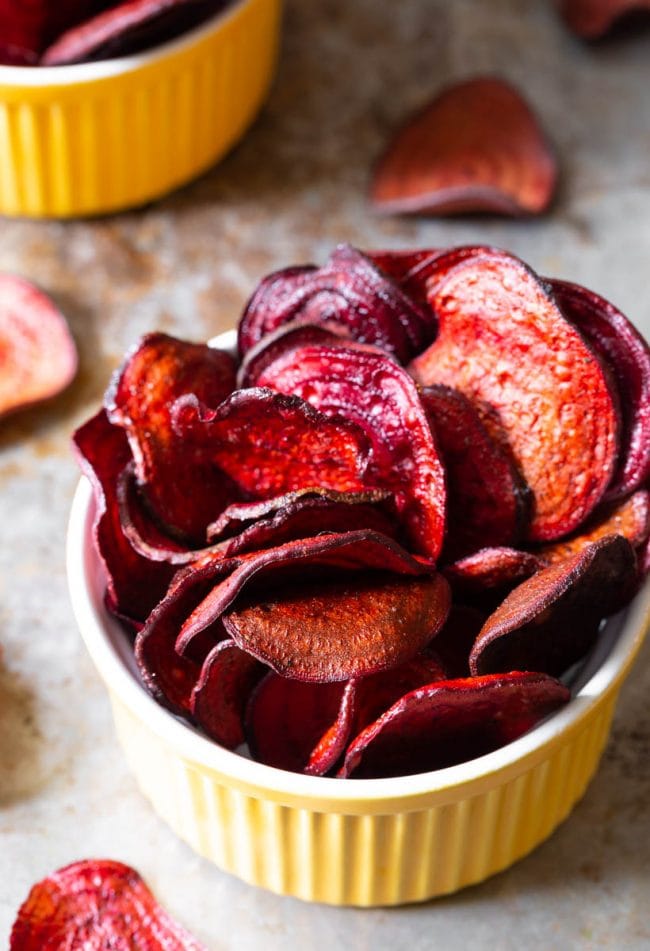 Top view of beet chips in a yellow ramekin. 
