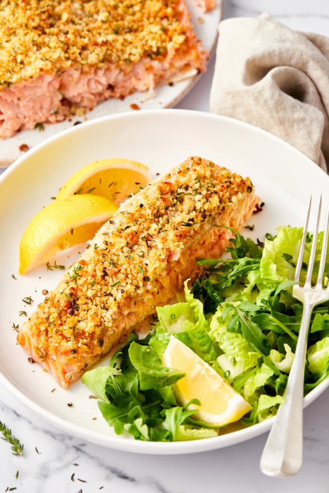 Salmon with a parmesan herb crust with a few bites missing at the end. 