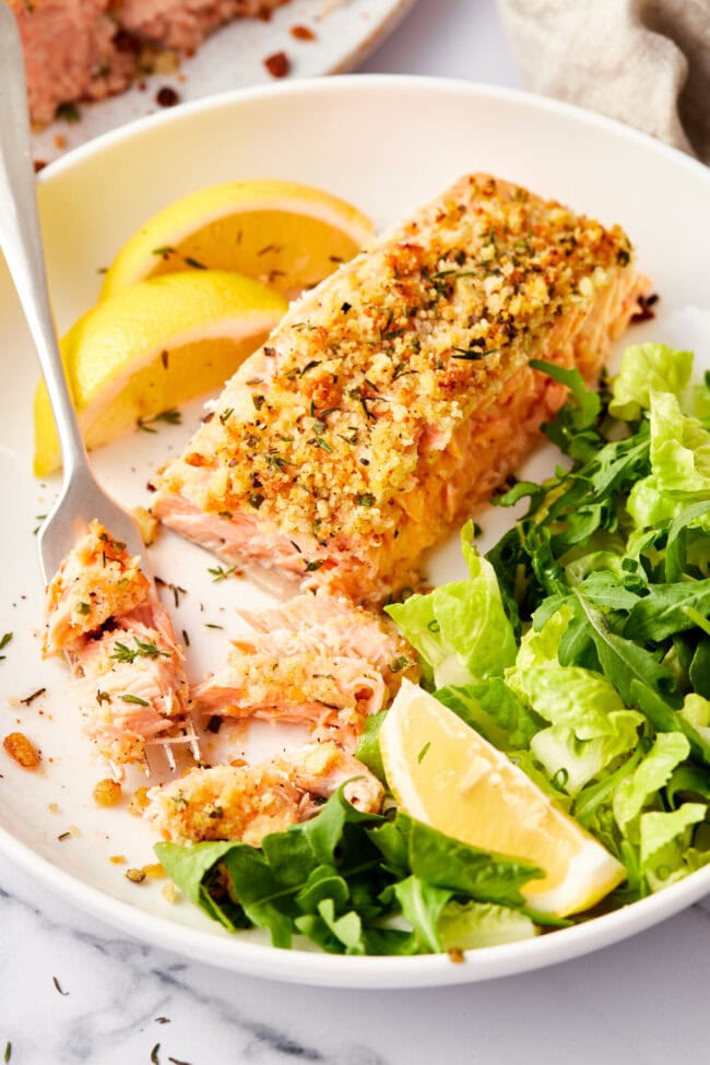 View of oven baked salmon with breadcrumb crust with some fish flaked off. 