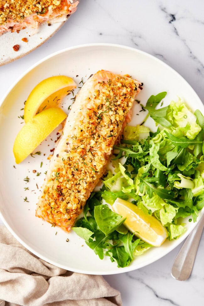 Oven baked salmon with a parmesan herb crust on a baking sheet with a spatula on the side. 