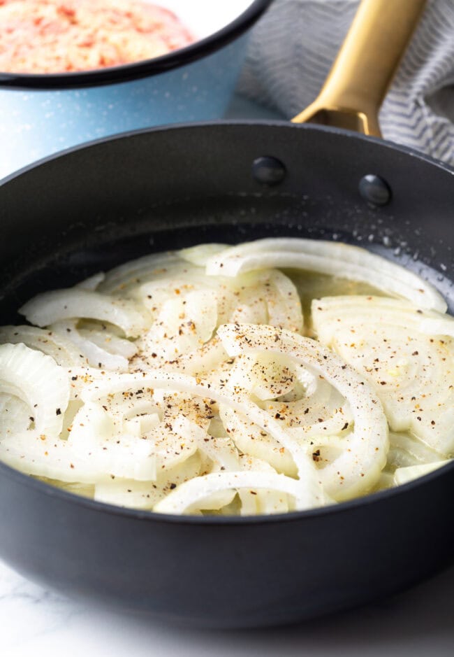 Raw onion slices in a skillet.