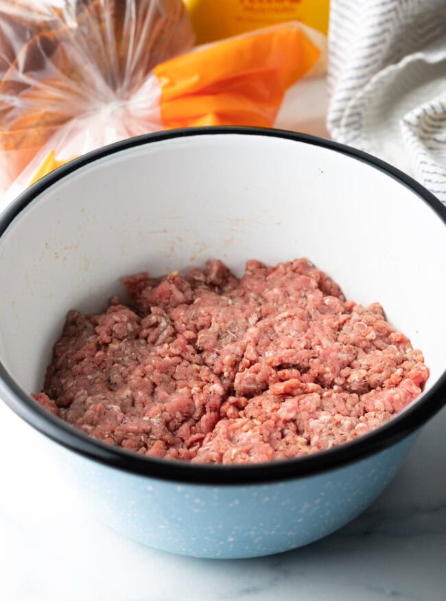 White bowl with raw ground beef.