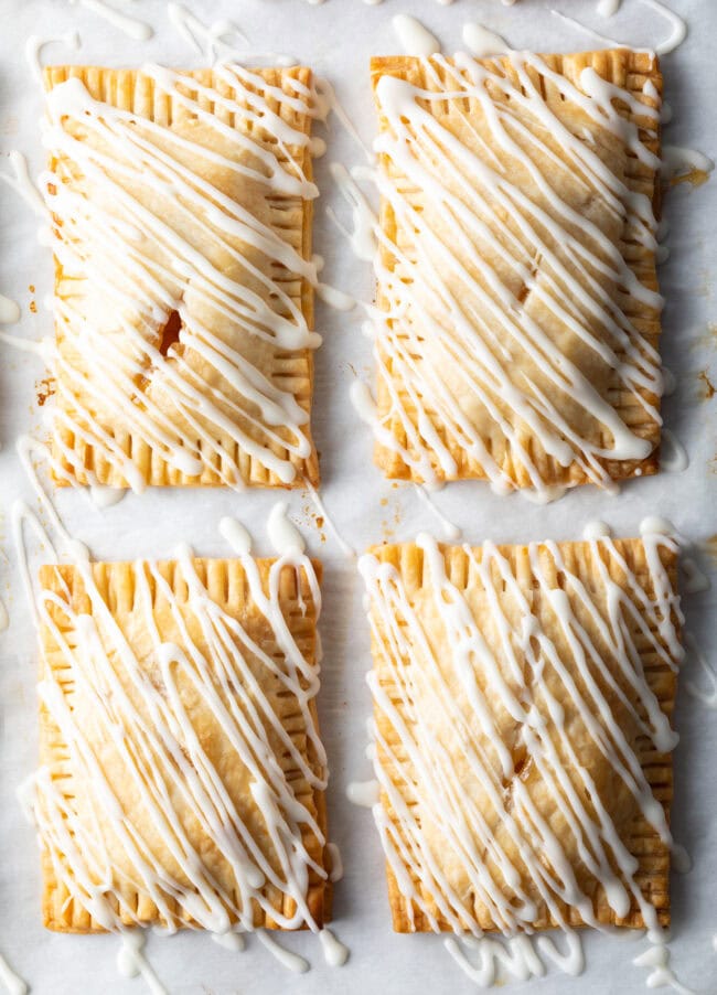 Top down view 4 finished peach hand pies, drizzled with white icing.