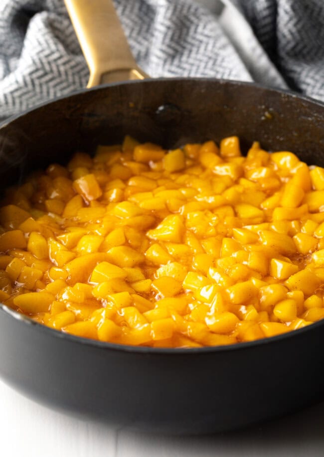 Peach mixture simmering in a large pot on the stovetop.