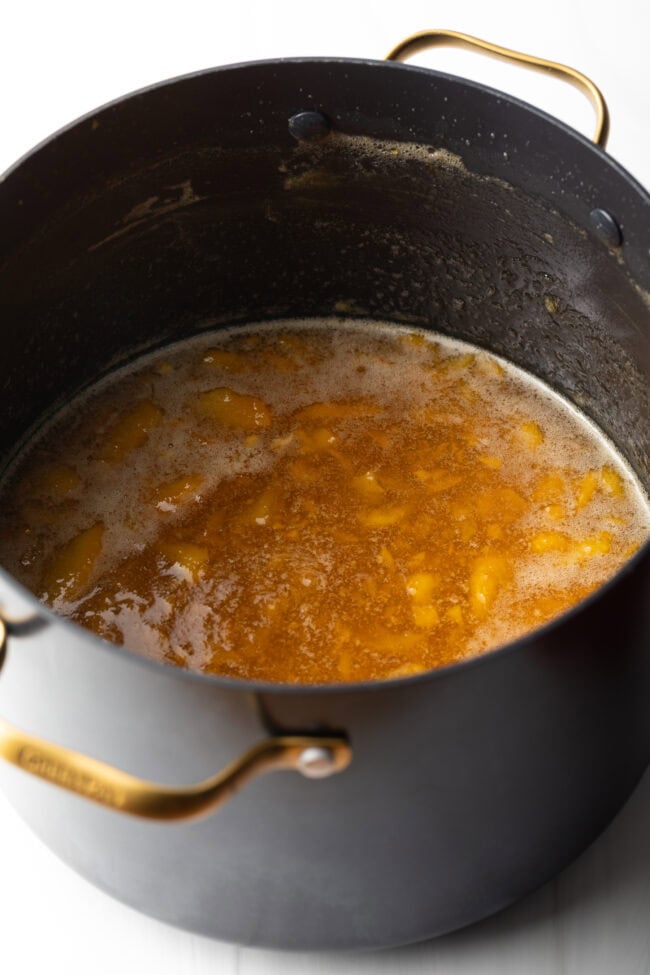 Cooking down the fruit in a large black pot.