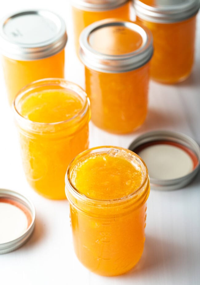 Multiple jars of peach preserves without lids.