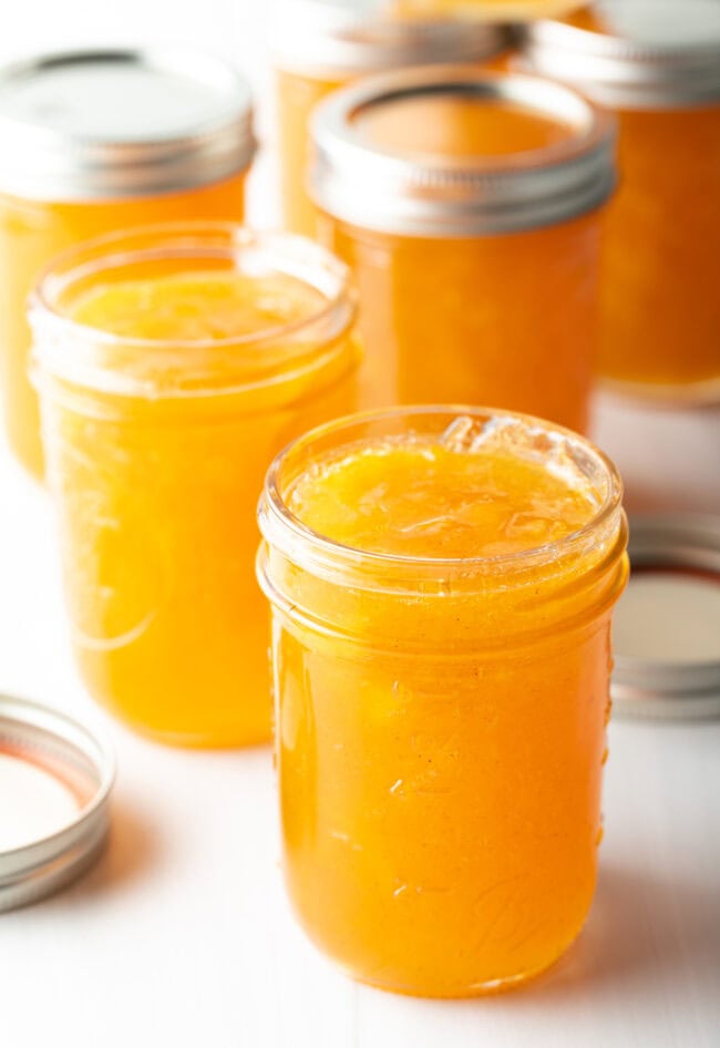 Multiple jars of peach preserves without lids.