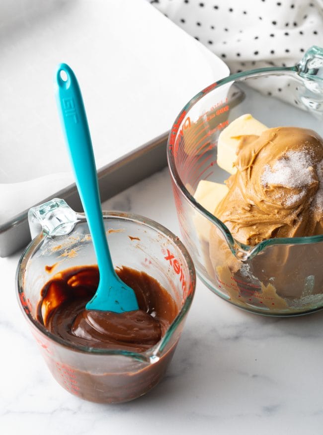 chocolate mixture in glass container, peanut butter and butter with confectioners sugar in another bowl