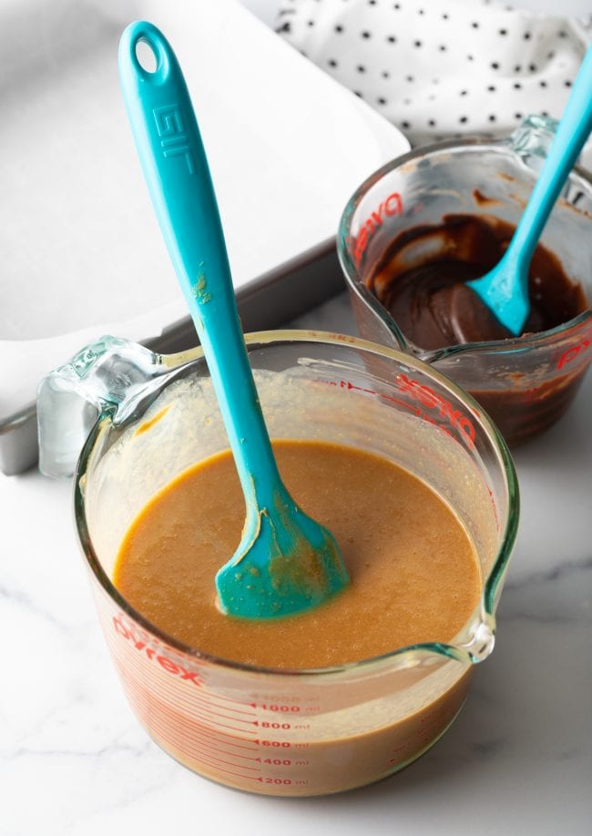 melted peanut butter mixture in a glass mixing cup with blue spatula