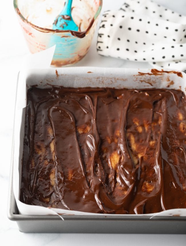 top view melted chocolate fudge topping added to top of peanut butter in baking pan