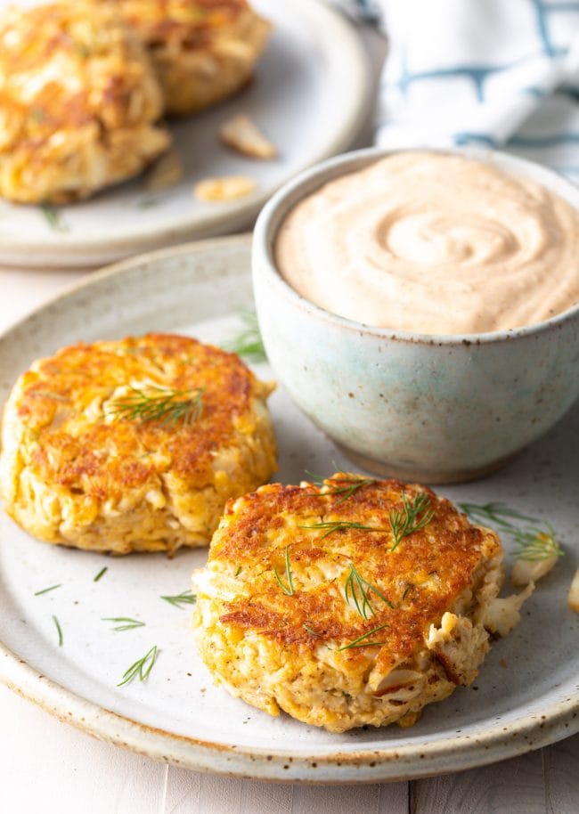 Maryland crab cakes served with side of dipping sauce on a plate. 