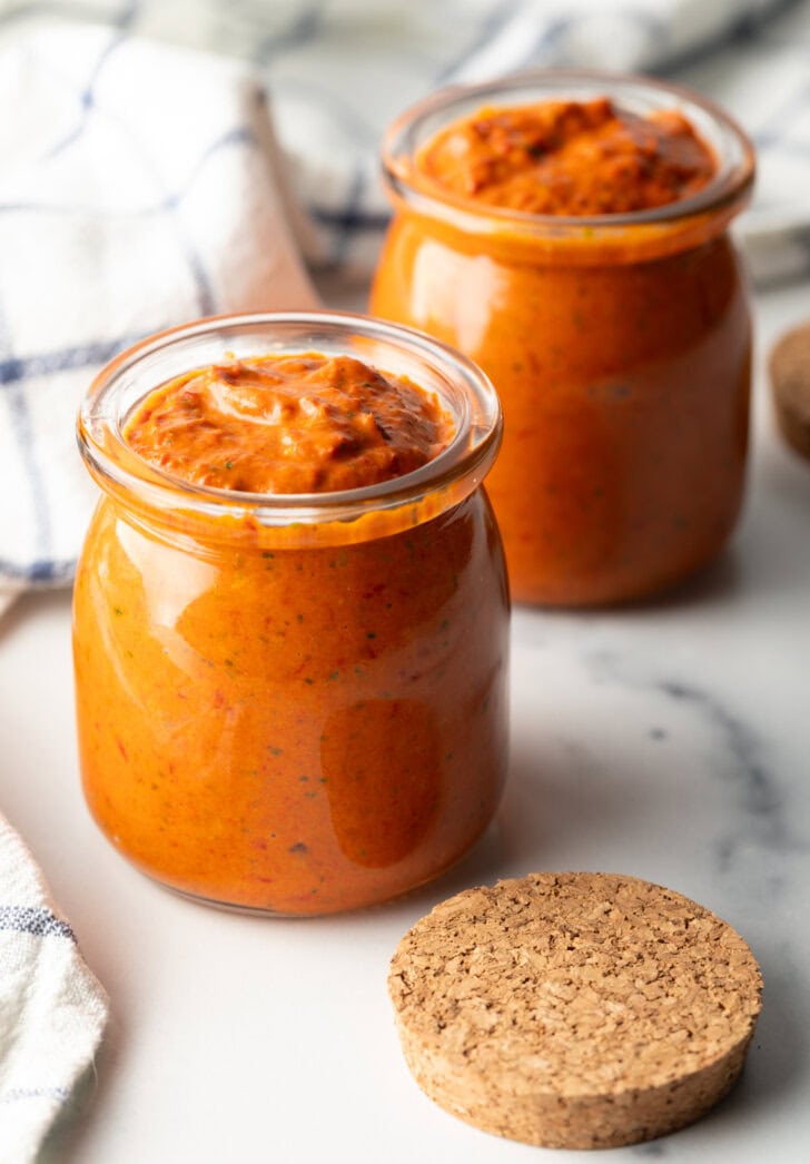 Two glass jars of thick peri peri sauce.