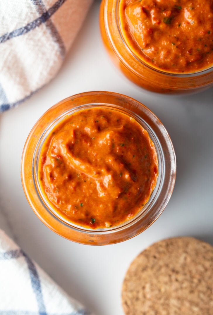 Top down two glass jars of thick peri peri sauce.