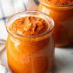 Two glass jars of thick peri peri sauce.