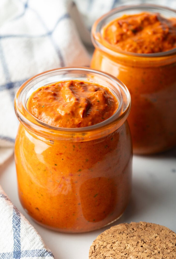 Two glass jars of thick peri peri sauce.