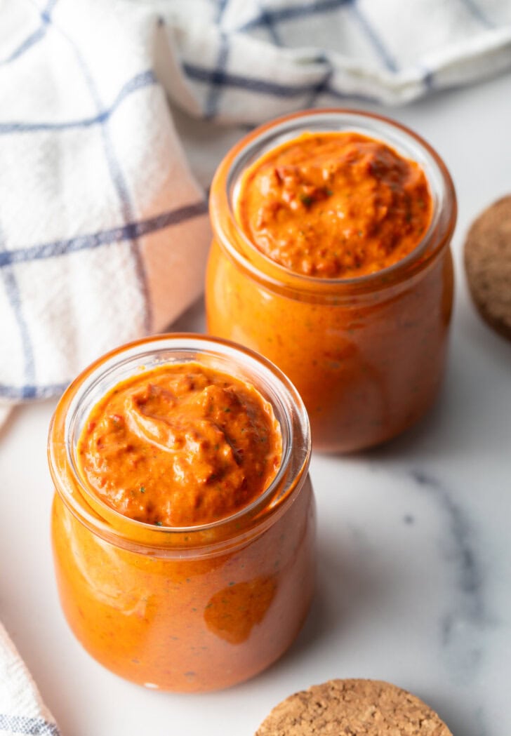 Top down two glass jars of thick peri peri sauce.