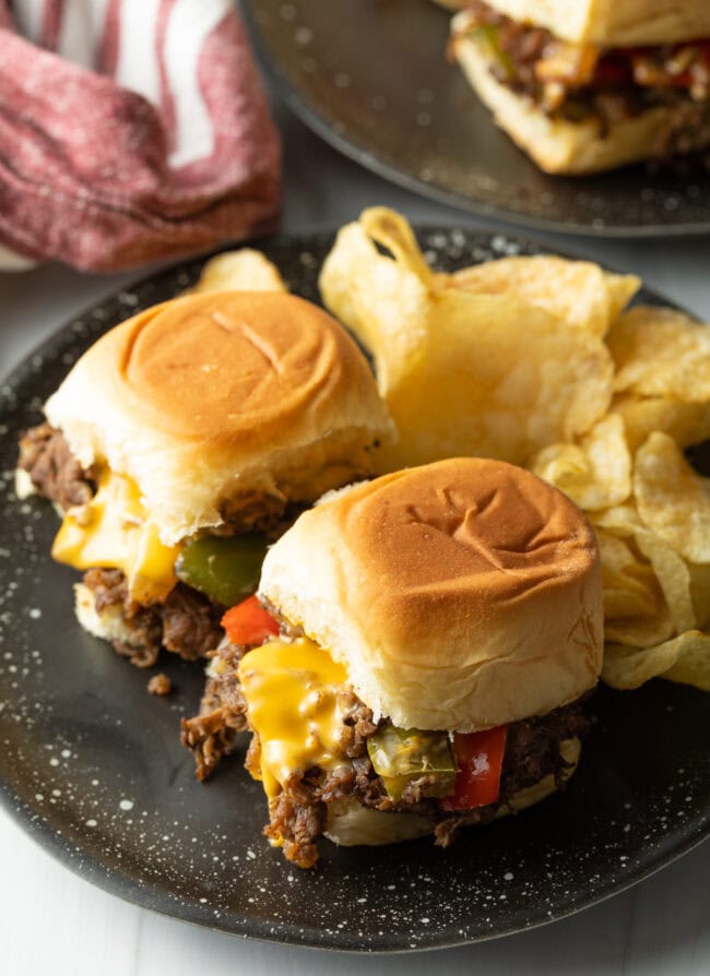 Top down two beef sliders on a plate with chips.