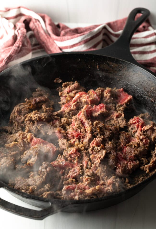 Cooking steak in a skillet.