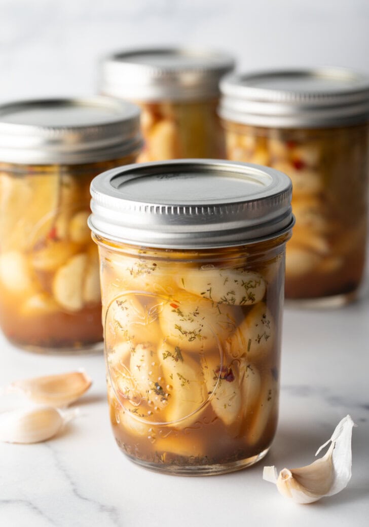 Glass jars of pickled garlic sealed with metal lids.