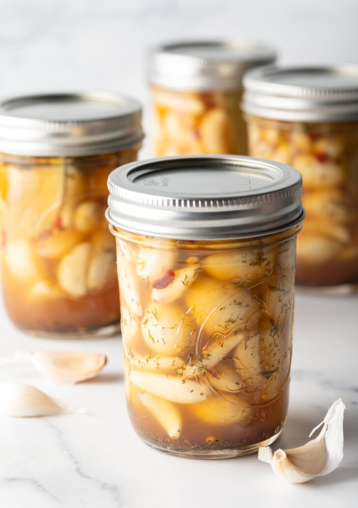 Glass jars of pickled garlic sealed with metal lids.