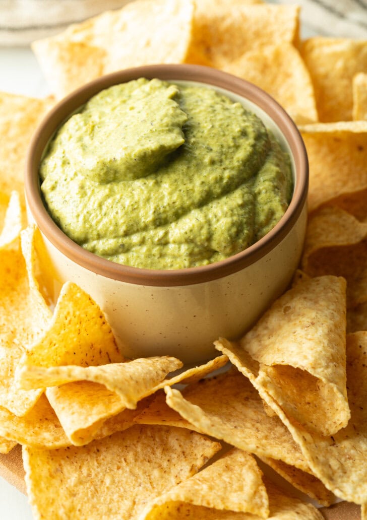 Small bowl of poblano cream sauce surrounded by tortilla chips