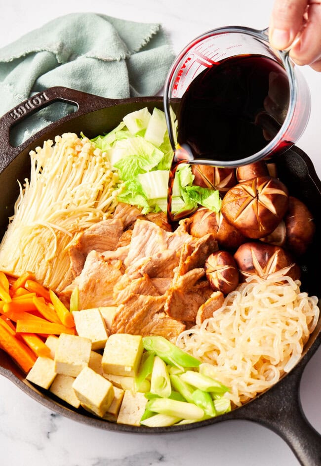 Traditional Pork Sukiyaki recipe in a skillet with sauce poured over top