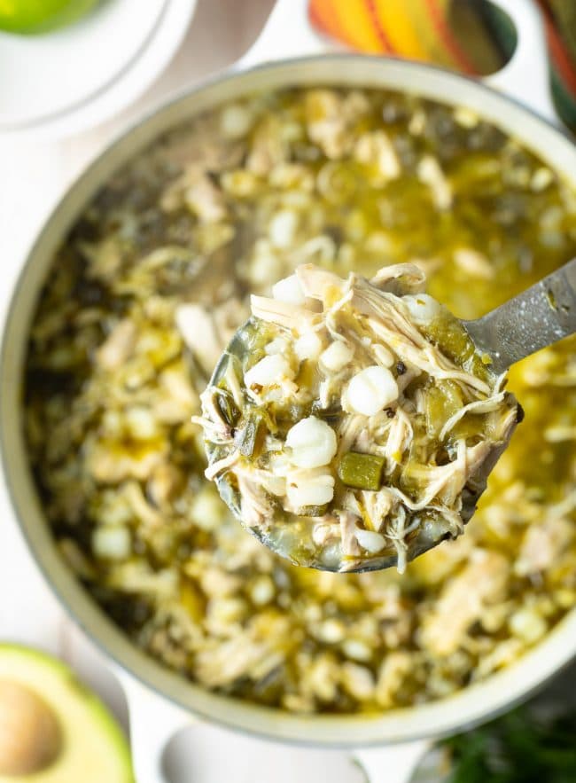 Ladle of Pozole Verde de Pollo lifted over the pot. 