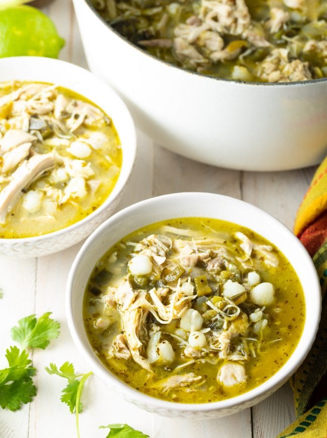 Bowls of green posole with the pot of pozole in the background. 