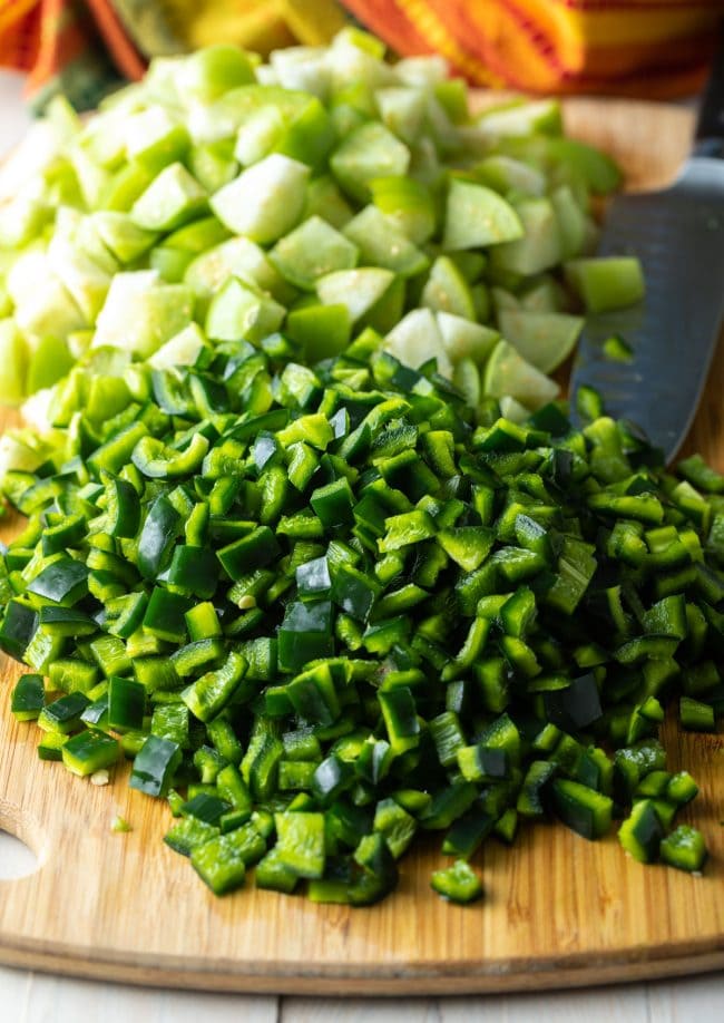 chopped peppers and tomatillos on a cutting board. 