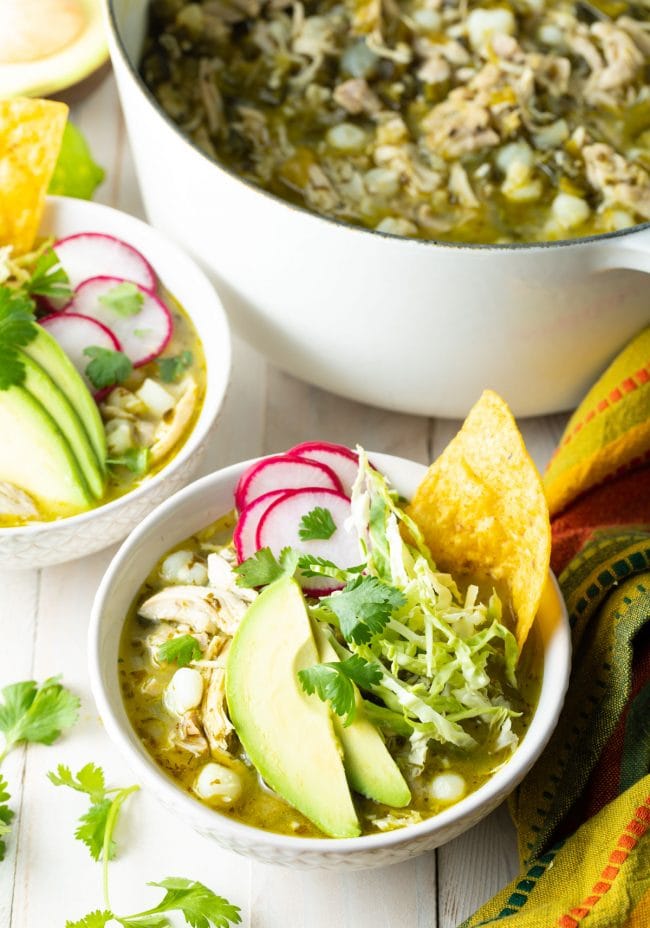 Pozole verde de pollo served in white bowls with toppings. 