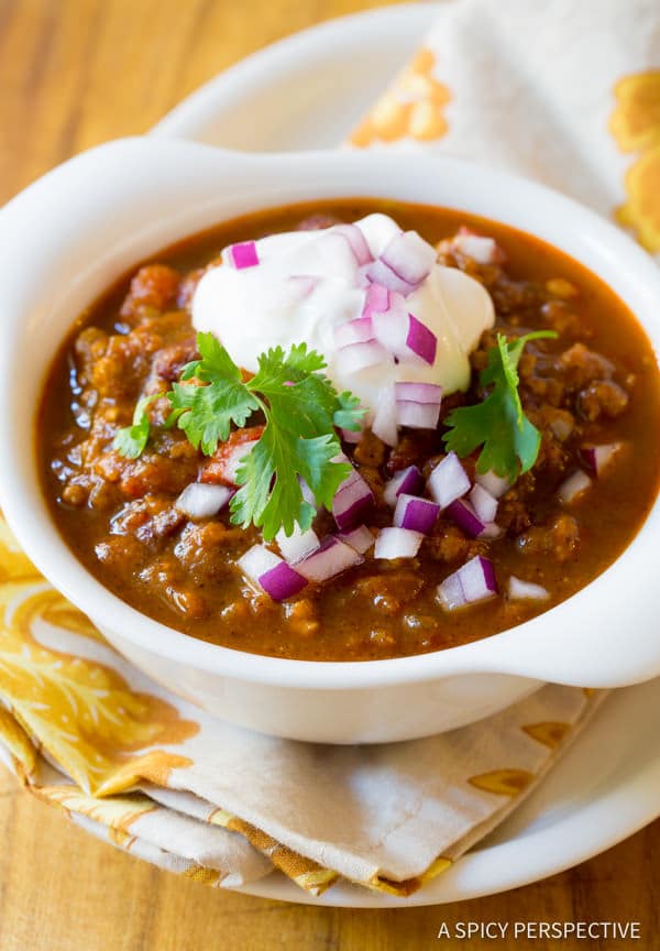 Pumpkin chili in a white bowl with toppings. 