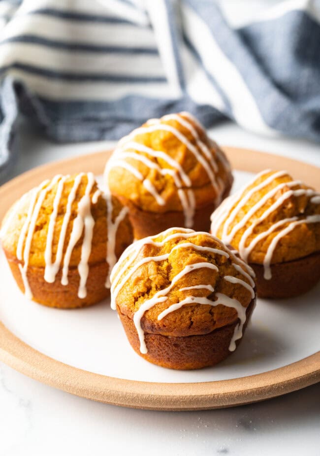 Plate with four pumpkin muffins drizzled with glaze.