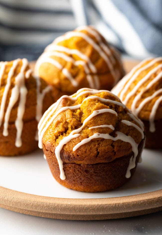 Plate with four pumpkin muffins drizzled with glaze.