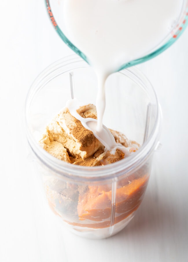 Adding milk to ingredients in a blender jar.