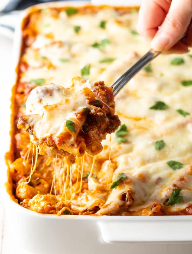 Ricotta Baked Ziti with Sausage with a serving spoon taking a scoop. 