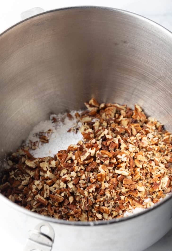 Crushed nuts in the bottom of a metal mixing bowl.