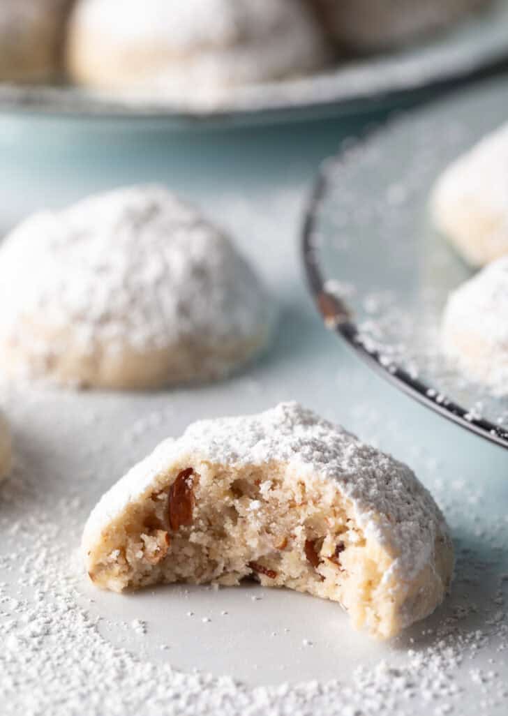 Close view of a Russian tea cookie with a large bite taken out.