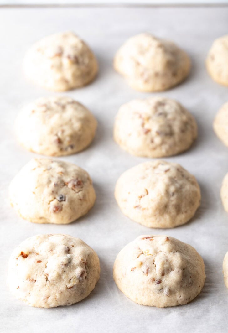 8 baked Russian tea cake cookies on parchment.