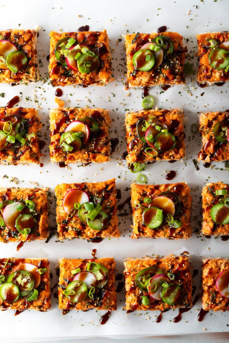 Rows of square slices of sushi bake on a baking sheet.