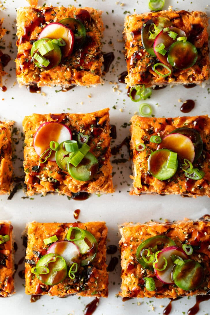 Rows of square slices of sushi bake on a baking sheet.